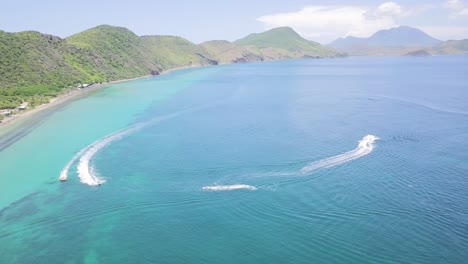 aerial view of a tropical island beach with turquoise water and jet skis