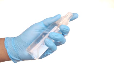 hand holding a spray bottle of sanitizer with blue gloves