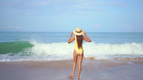 Una-Mujer-Saludable,-En-Forma-Y-Sexy-En-Traje-De-Baño-De-Espaldas-A-La-Cámara-Observa-Una-Gran-Ola-Acumulada-En-La-Playa