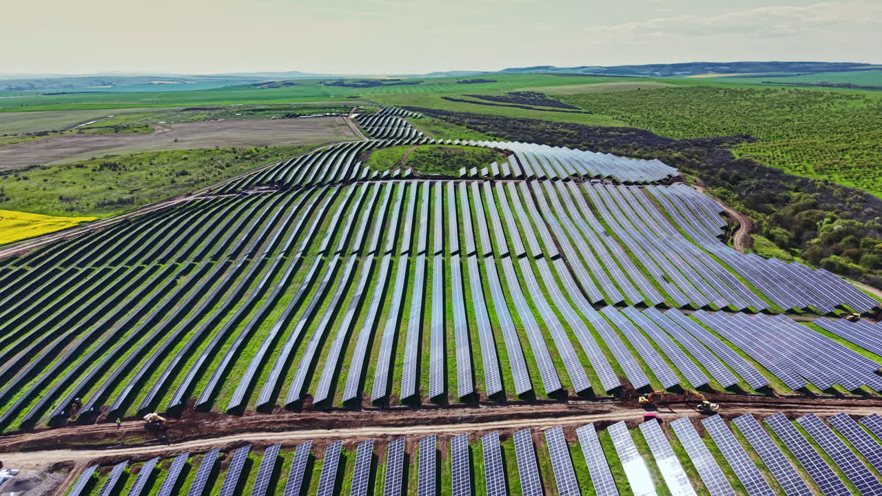 Solcelleinstallation på en stor mark i et landområde om dagen med klar himmel og grønne omgivelser