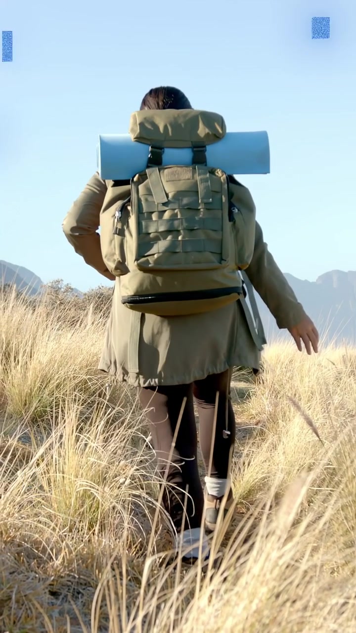 Video verticale: Donna escursionista che fa il primo passo dirigendosi verso le cime, con quadrati blu che pulsano sullo zaino.