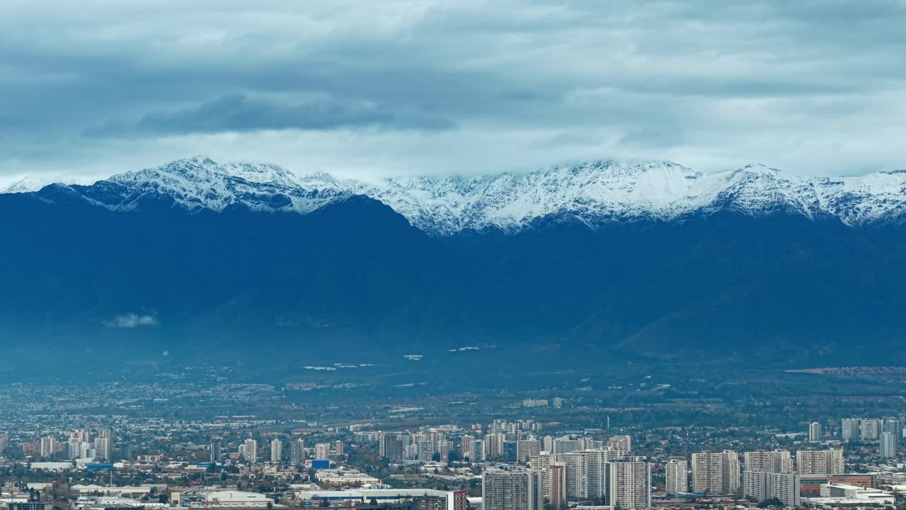 Snowy Andes mountain range with urban city view under cloudy sky in Colombia