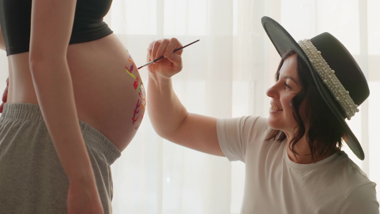 Artista che dipinge un disegno colorato sulla pancia di una donna incinta