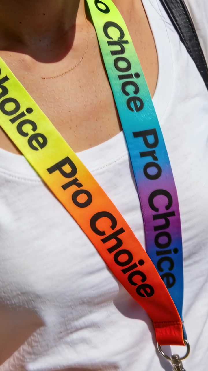 Vertical video: Swaying torso shifting ProChoice lanyard on white tank in sun, revealing clasp
