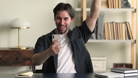 el hombre lee el correo electrónico en el teléfono móvil tiene noticias increíbles se siente feliz