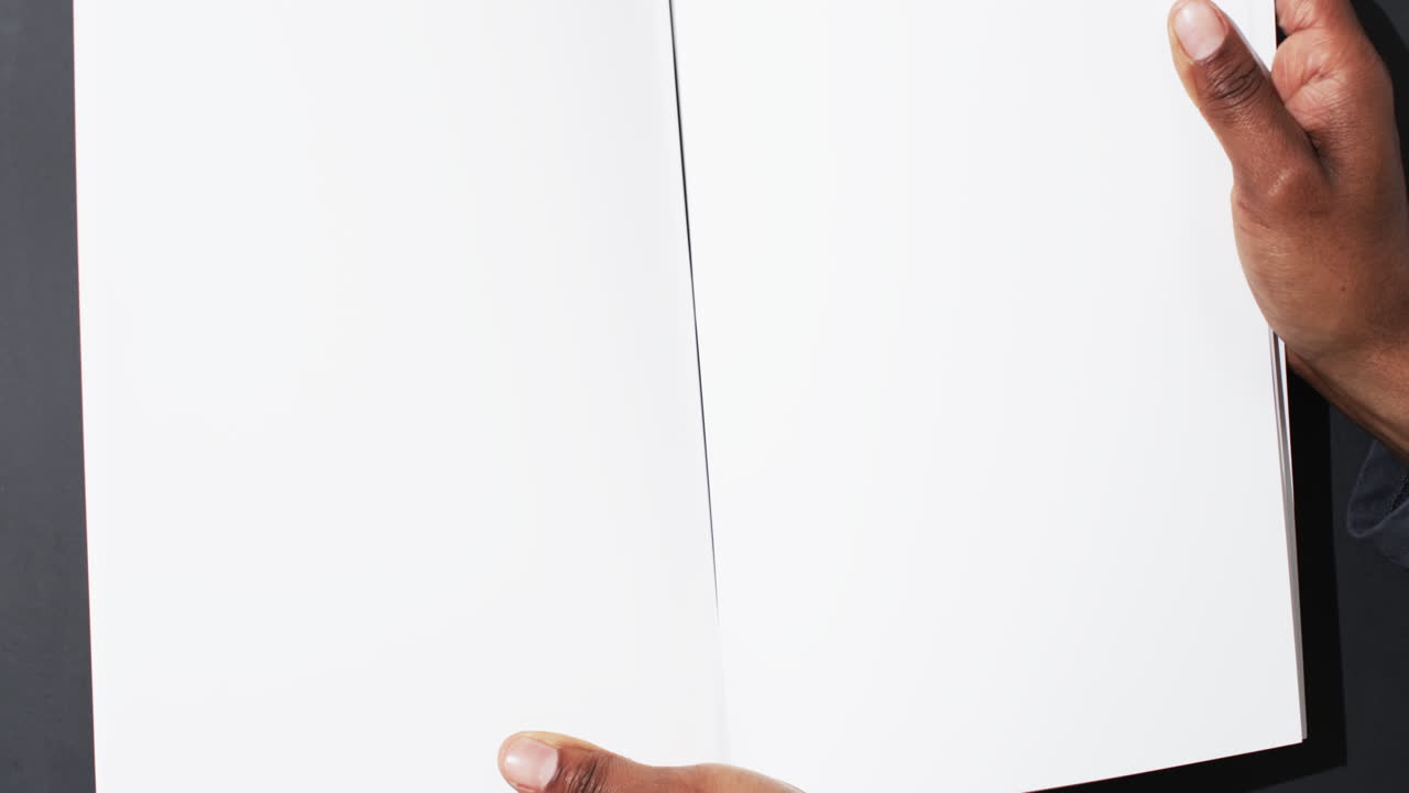 video de la mano de un hombre afroamericano sosteniendo un libro con páginas en blanco, espacio de copia en fondo negro