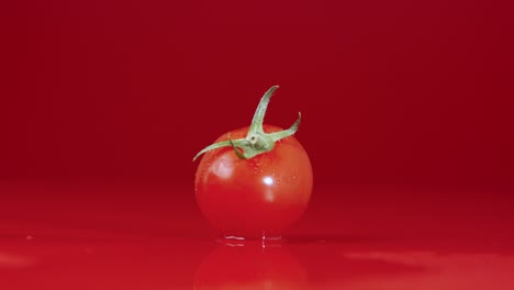 close-up of a single cherry tomato on a red background