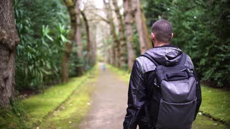 Sportsman-rearview-trekking-a-track-trail-through-mountains-walking-by-muddy-paths-after-rain-amidst-nature-in-the-middle-of-the-forest-and-jungle