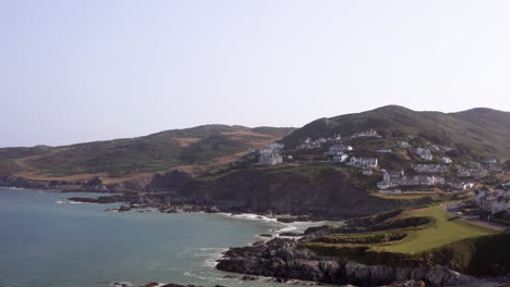 Aerial-Flyover-of-Rocky-Beach-in-North-Devon-with-a-Car-Driving-Up-the-Hill