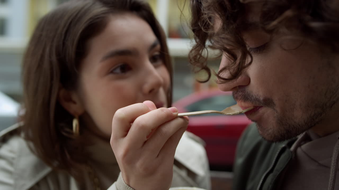 Coppia innamorata che ha un appuntamento romantico all'aperto. Donna che dà da mangiare all'uomo in una strada urbana.