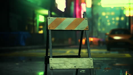 construction barrier on a wet street in a vibrant urban setting at night