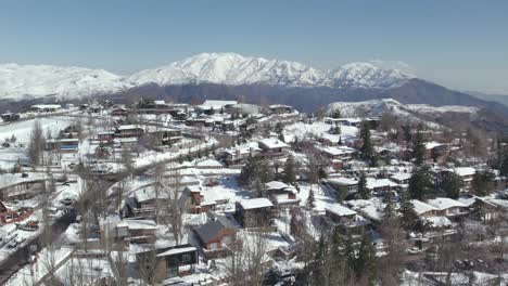 vista aérea de la ciudad de esquí con montañas cubiertas de nieve en el fondo, toma de movimiento de paralaje