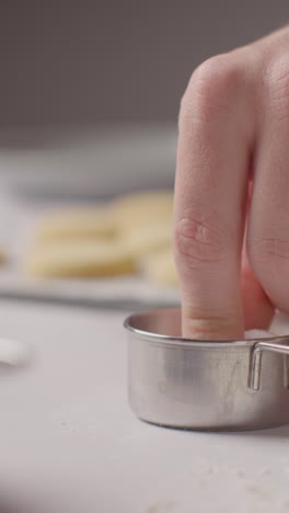 video vertical de una persona rociando azúcar en galletas de pan corto caseras en una bandeja en la superficie de trabajo de la cocina