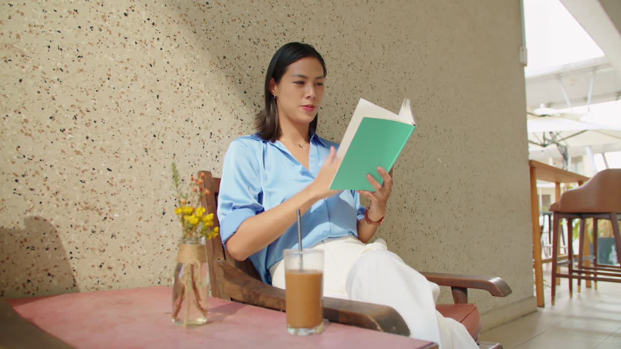 Young Businesswoman Relaxing in Outdoor Cafe with Book