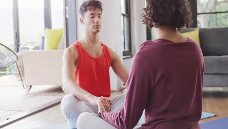 Happy-diverse-male-couple-doing-yoga,-meditating-in-living-room