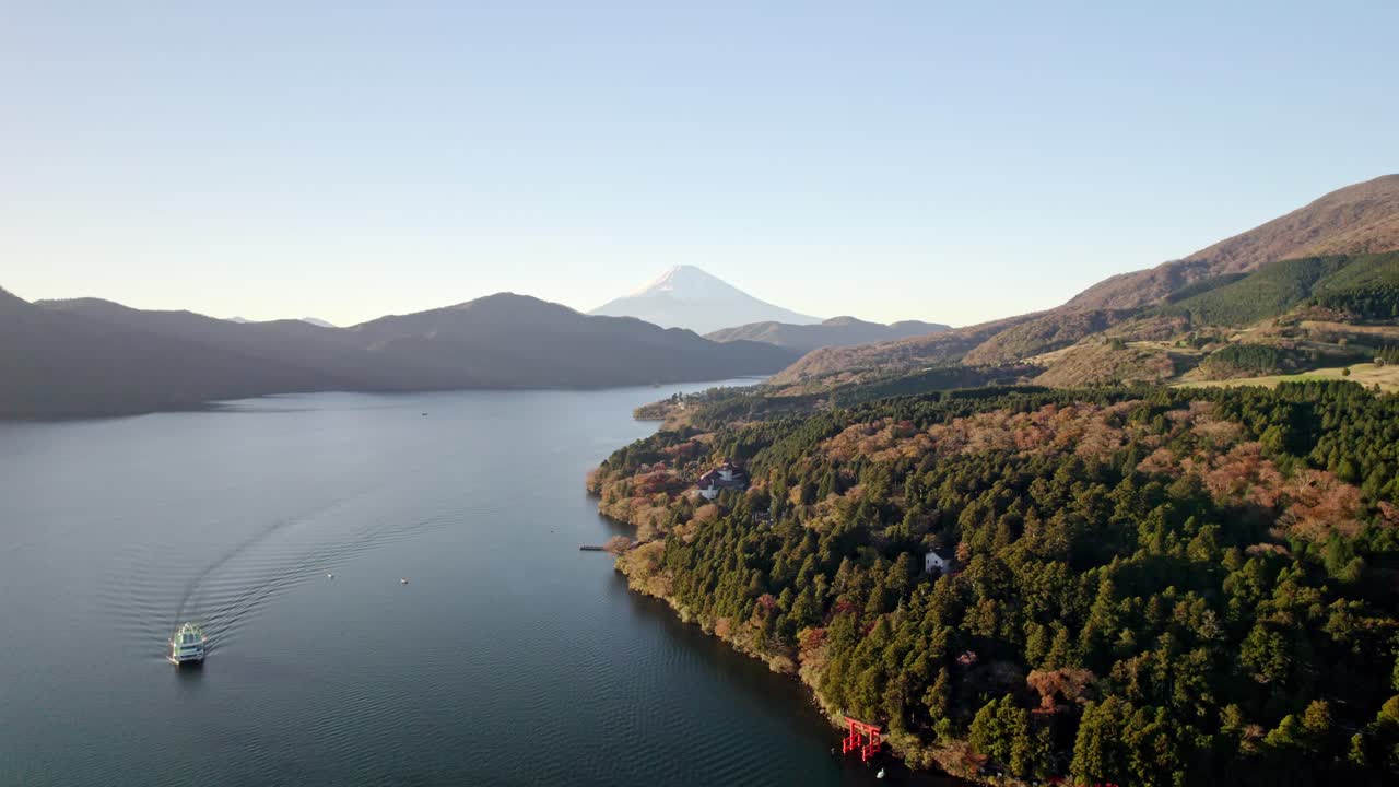 Aerial drone shot of a calm Japanese lake with Mount Fuji rising in the distant background
