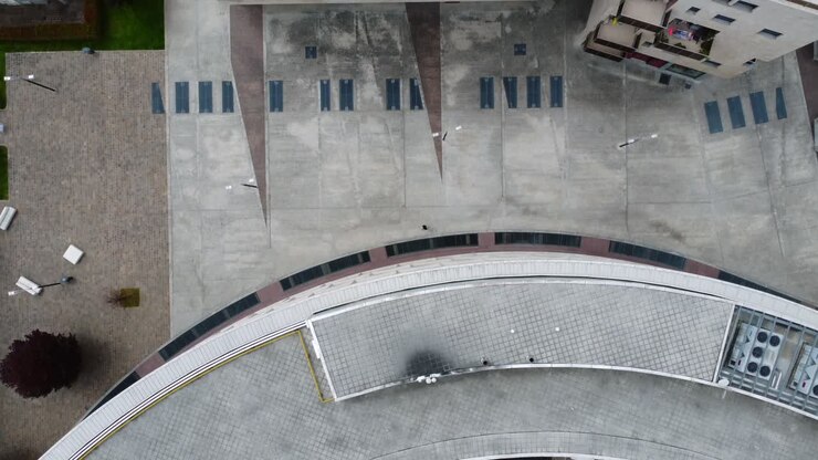 Aerial view capturing a modern rooftop pool area with solar panels, loungers, and minimalistic design, highlighting urban luxury and eco-friendly architecture in a birds-eye view