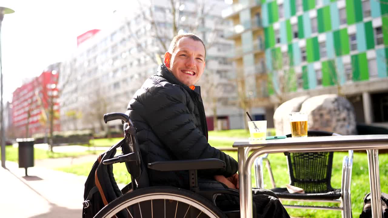 Mann im Rollstuhl genießt ein Getränk im Freien