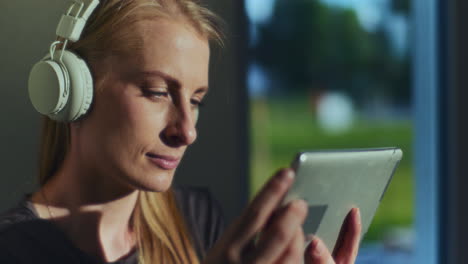 concentrated woman uses digital tablet and wireless headphones