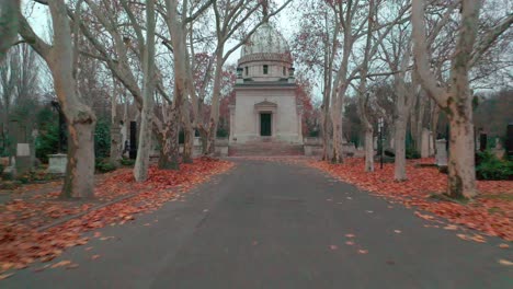 autumnal path leading to a mausoleum in a historic cemetery