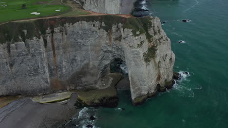 Breathtaking-Tilt-down-on-Etretat-Cliff-Arch-with-People-walking-over-steep-Cliff-Edge