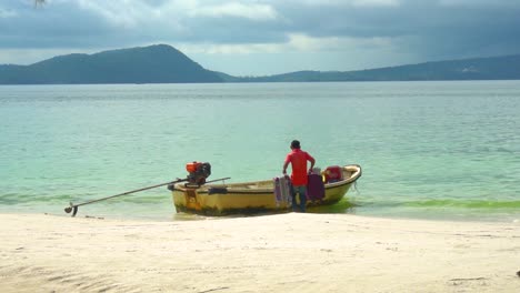 El-Hombre-Carga-Maletas-De-Viaje-En-Un-Pequeño-Bote-De-Taxi-Acuático-En-La-Orilla-De-Una-Playa-Tropical