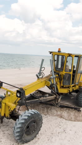 yellow road grader working on a beach