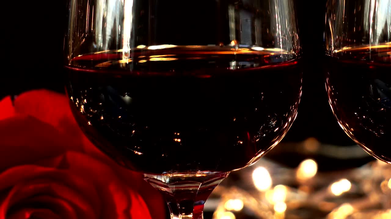 Taças de vinho e rosa contra o fundo de guirlandas brilhantes