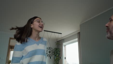 adolescente caucásica y su padre jugando a un videojuego con un controlador de juego