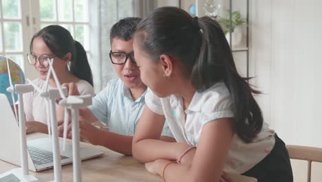 young asian children work as a team using laptop computers to program wind turbines. classroom with kids learning about eco-friendly forms of renewable energy