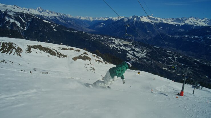 Snowboarder che esegue curve fluide e un 180 pulito su una pista battuta ad Anzère, Alpi Svizzere. Flusso freestyle giocoso, sfondo panoramico della valle ed energia dinamica degli sport invernali sotto un cielo sereno.