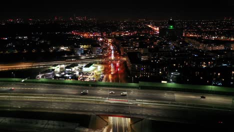 Drohnenaufnahme-Des-Nächtlichen-Verkehrs-Auf-Einer-Autobahn-Mit-Autos-Und-Lichtspuren-Mit-Tunnel-Und-Viadukten-Außerhalb-Der-Stadt-Warschau,-Polen