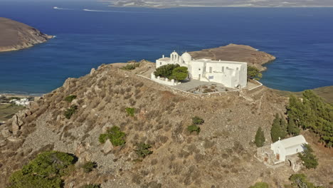 paros grecia antena v9 órbita tiro drone volar alrededor del monasterio de agios antonios en lo alto de una colina rocosa, iglesia con impresionantes vistas panorámicas de la costa y el paisaje de paros - septiembre de 2021