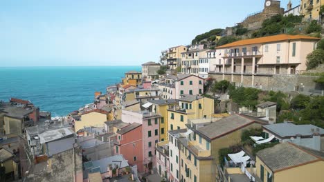 Vista-Aérea-Volando-A-Través-De-Riomaggiore,-Cinque-Terre-Hacia-El-Mar-De-Liguria.