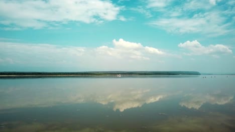 flying over calm waters of lake magadi to the flamboyance of flamingo foraging food at daytime