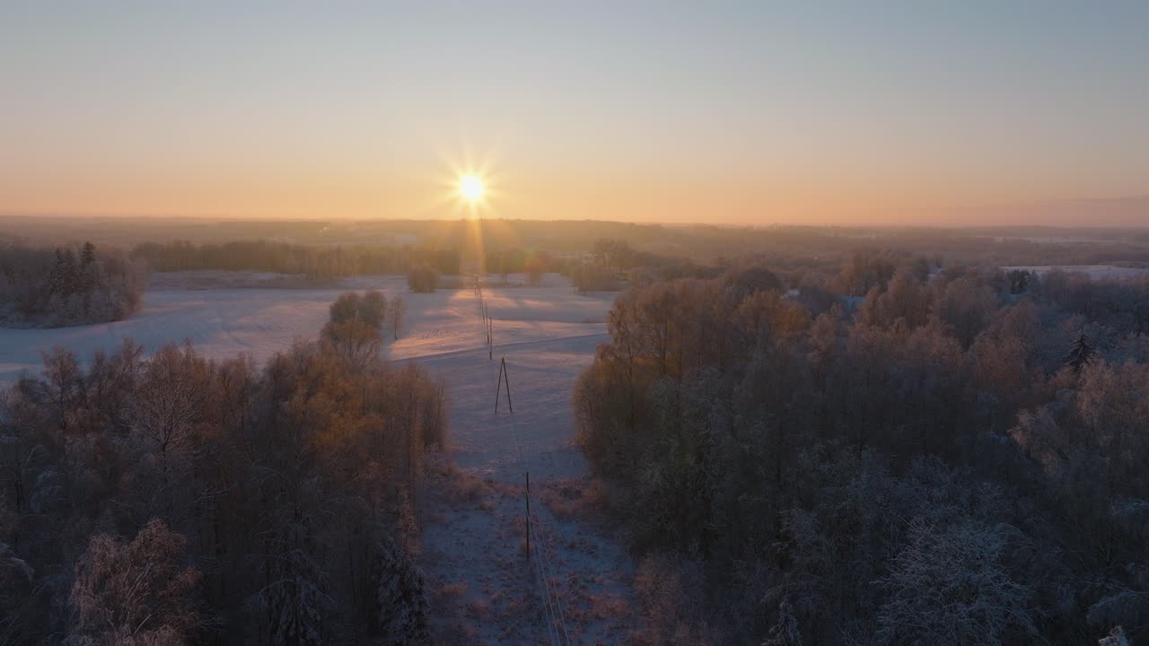 Aerial establishing view of a rural landscape in winter, snow covered countryside fields, cold freezing weather, sunset with golden hour light, wide drone shot moving forward