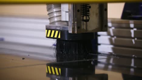 a cnc router head moves with precision, cutting black signage in slow motion with debris flying off