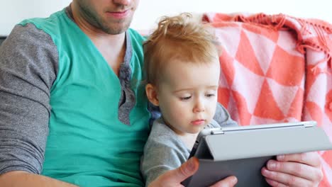 Father-with-his-baby-boy-using-digital-tablet-in-living-room-4k