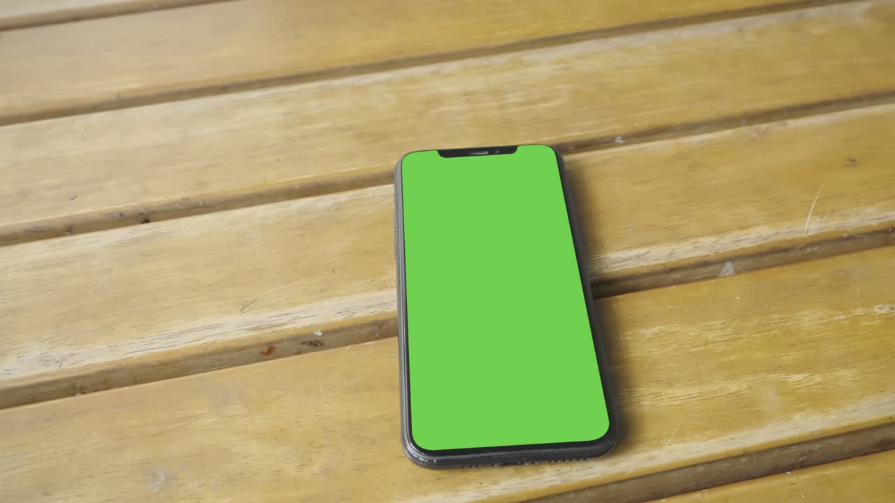 Smart phone place on table wood, Green screen telephone, Close up display mobile phone with mock up, Chroma key monitor, Blank of mockup smartphone, Hand held top view.