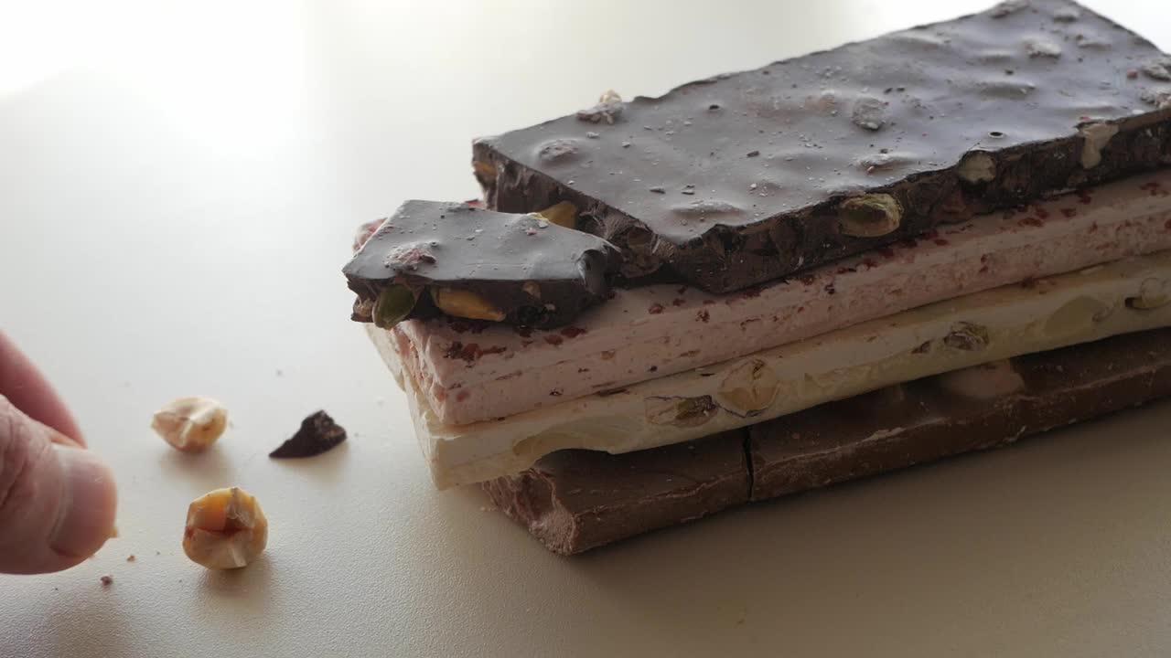 Assorted dark and white chocolate bars decorated with nuts on a clean white background. Great for showcasing gourmet chocolate treats.