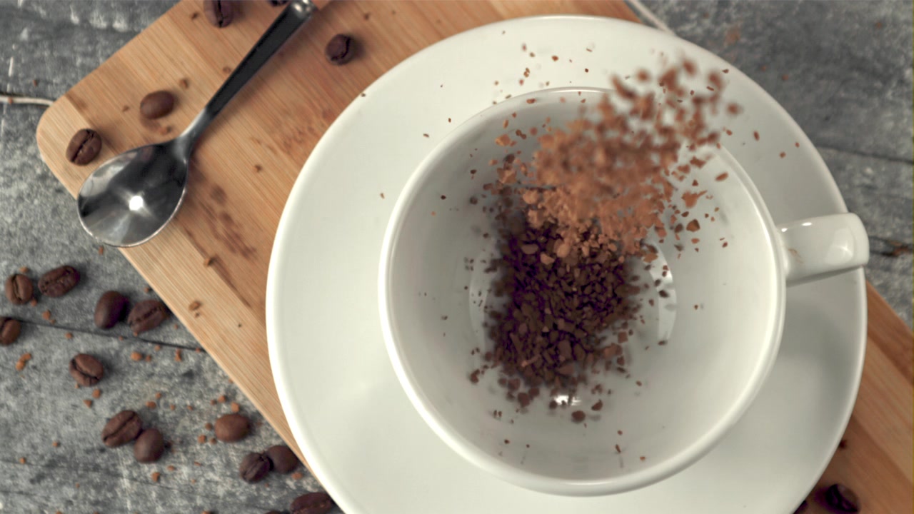 Sakte film av pulverkaffegranulat som faller ned i en hvit kopp