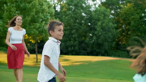 excited boy and girl jumping in field. joyful family playing with ball