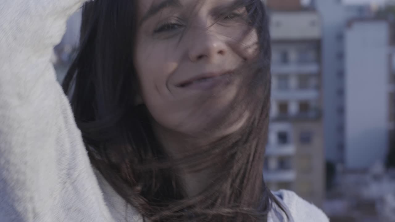 Primo piano di giovane donna sorridente con i capelli mossi dal vento