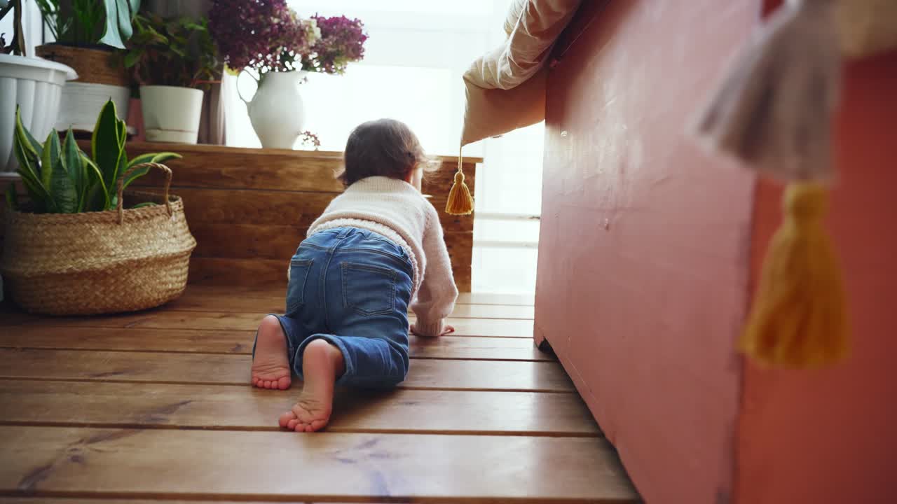 Simpatica bambina piccola che gattona sul pavimento in legno a casa