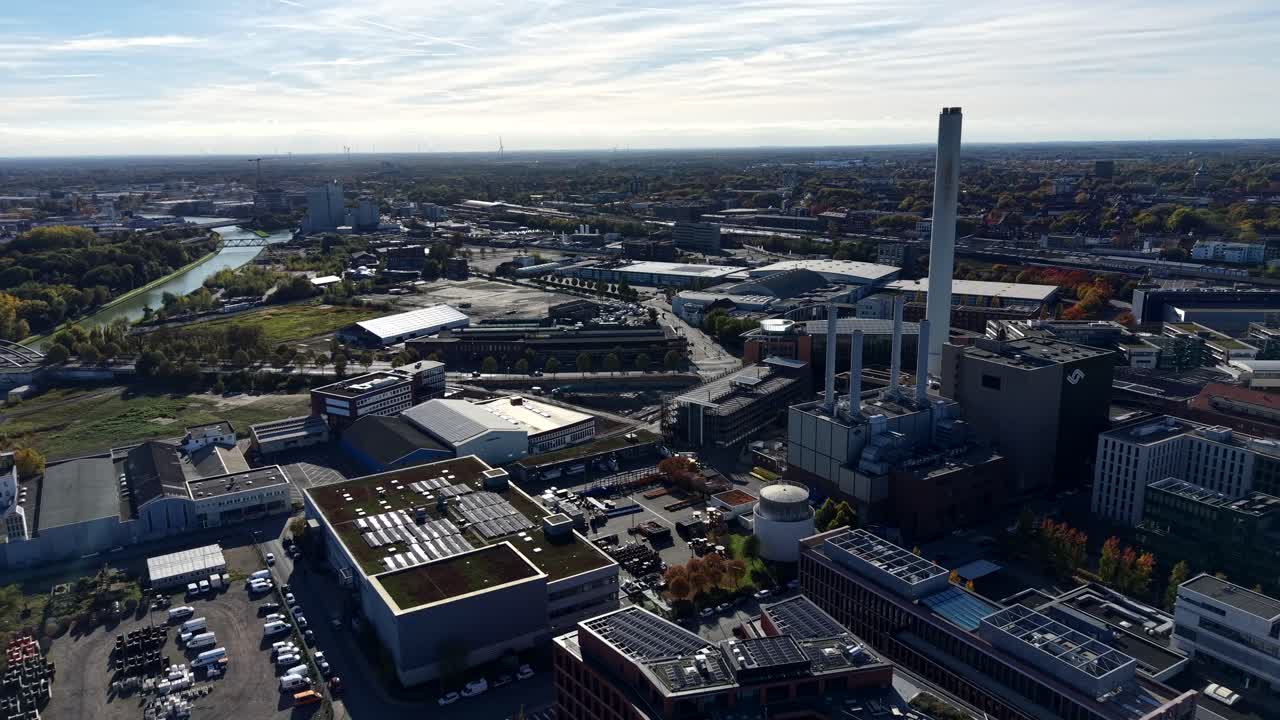 Industrial district of american town during sunny day with tower. Solar panels on roof of buildings and urban. Sunny day in autumn. River with cityscape in distance. Aerial lateral wide shot