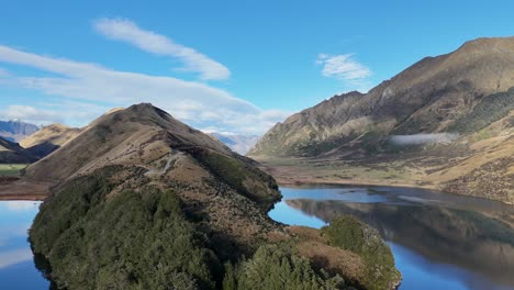 drone captures serene lake moke and surrounding mountains under clear blue skies, showcasing natural beauty and tranquility
