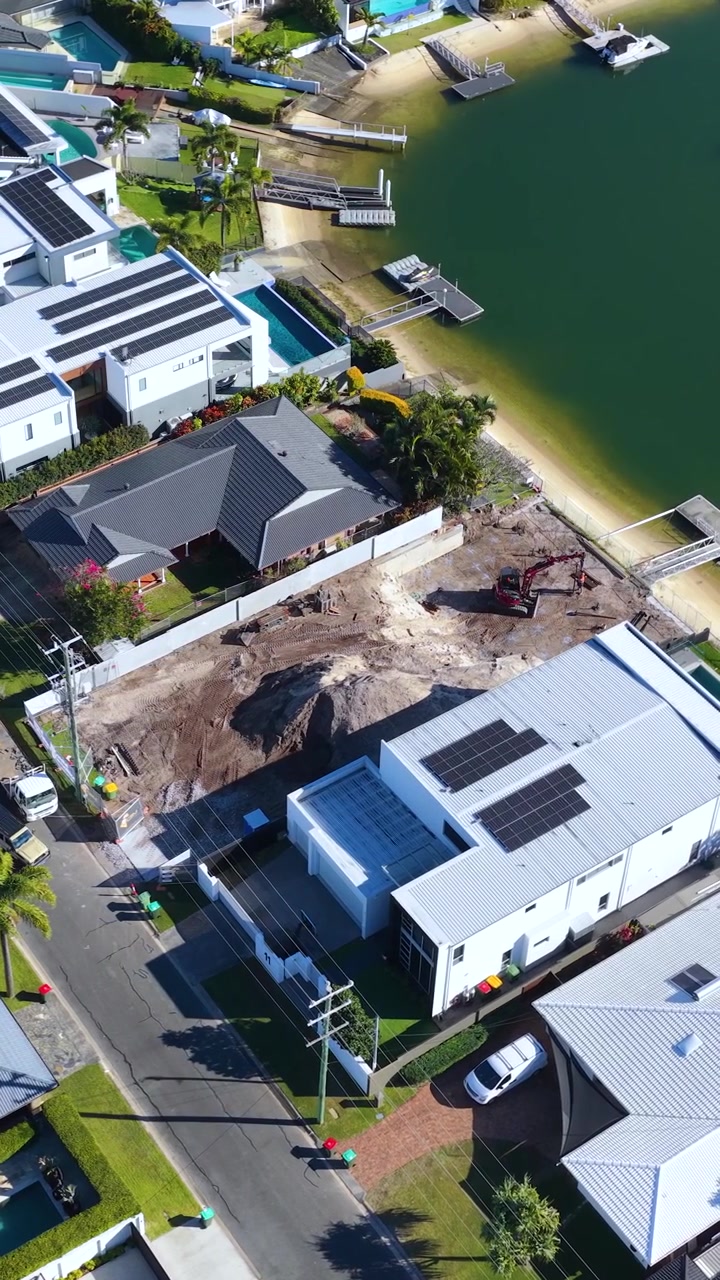 High-angle drone shot of luxury homes and a construction site in Broadbeach Waters, Australia.