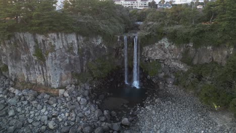 drone aerial view in south korea flying in front of a waterfall over the sea rocky area still jeju island