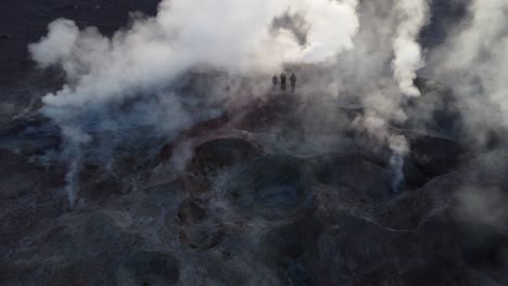 Luftaufnahme:-Touristen-Stehen-Im-Gegenlicht-Zwischen-Dampfenden-Geysiren-Am-Sol-De-Manana