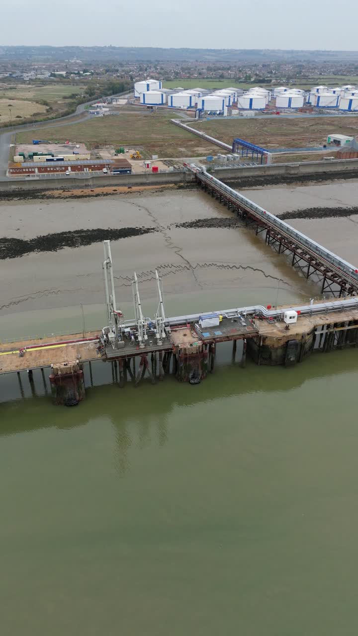 High-angle drone footage capturing Canvey Island fuel terminals with extensive pipelines, storage silos, and piers for maritime fuel imports and exports